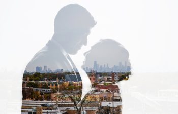 A silhouette of two people against a city backdrop