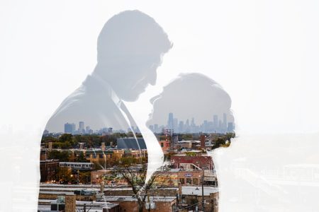 A silhouette of two people against a city backdrop