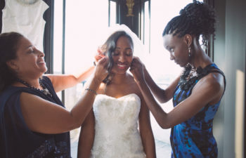 A bride is getting her earrings put on by her family.