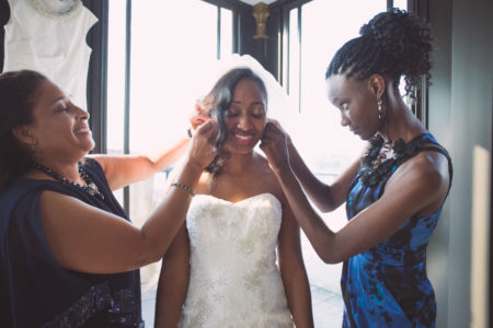 A bride is getting her earrings put on by her family.