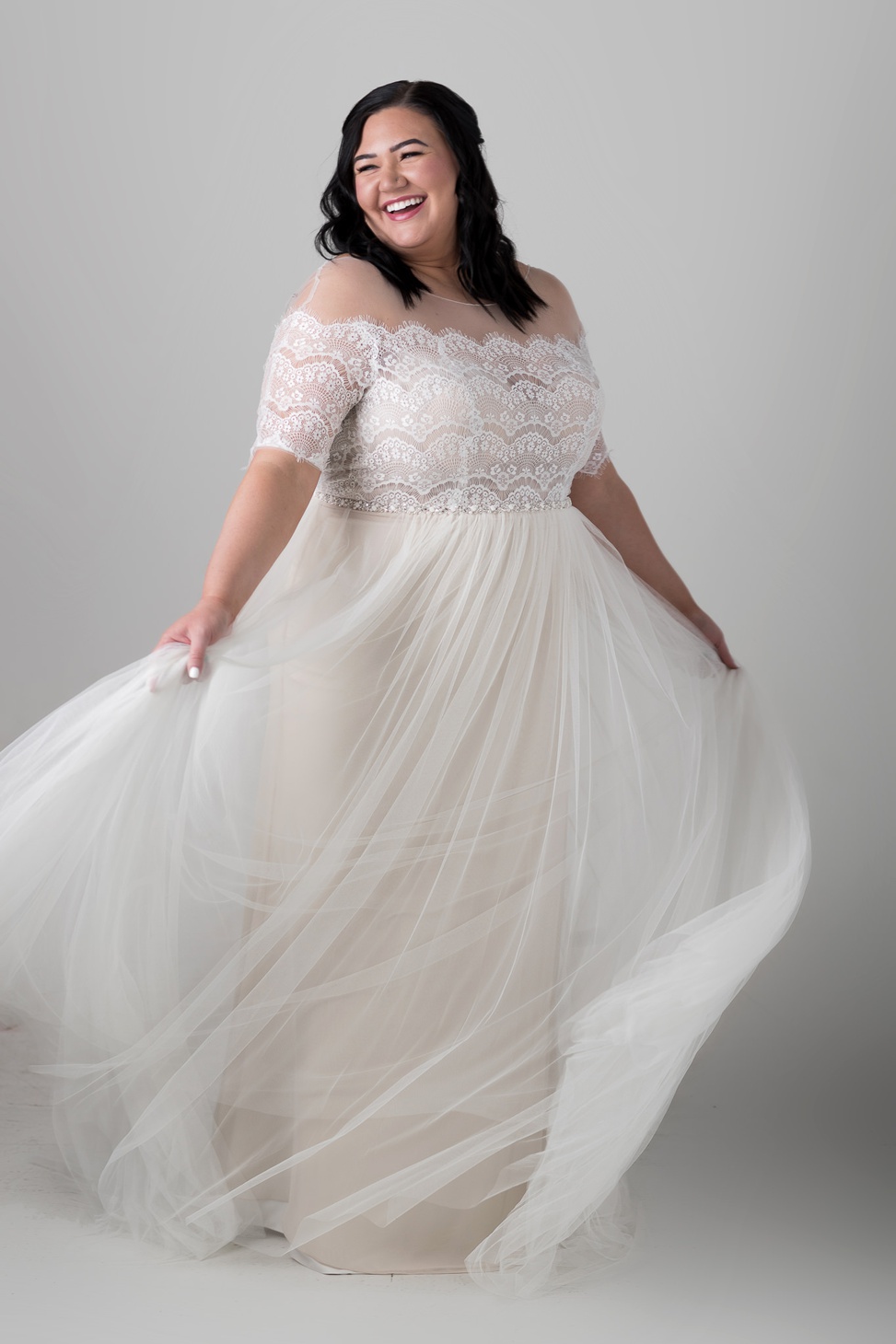 a plus size bride smiles and twirls in the cathy dress from rebecca ingram
