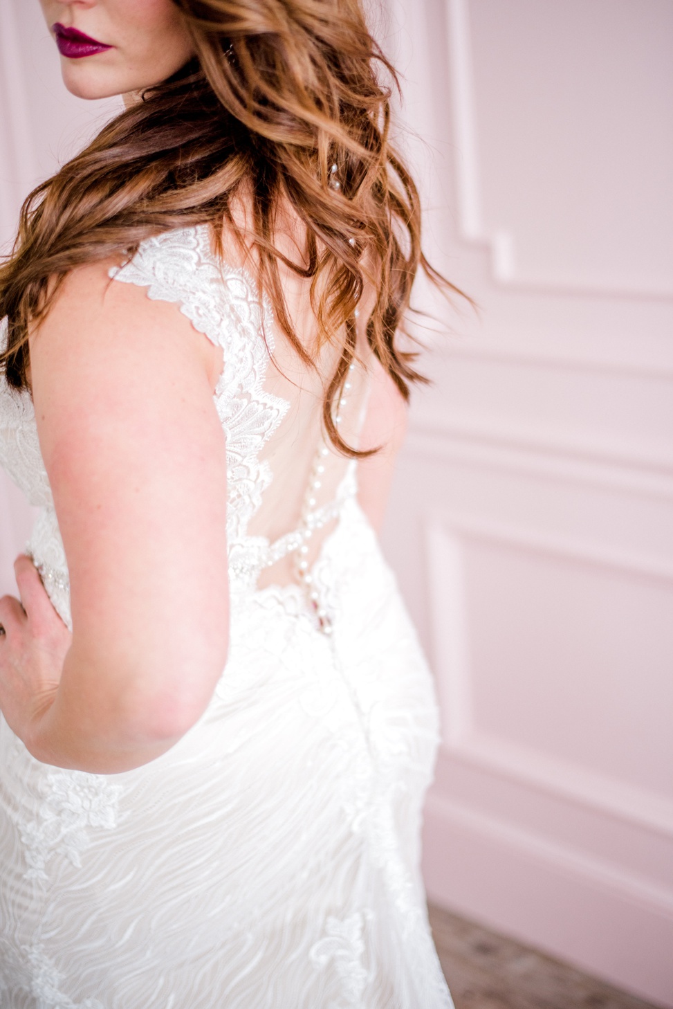 a closeup of a redhead bride wearing the wyatt dress with a sheer back and cascading buttons from sottero and midgley