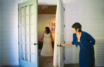 A mother of the bride opening a door and peaking in on her daughter about to wed