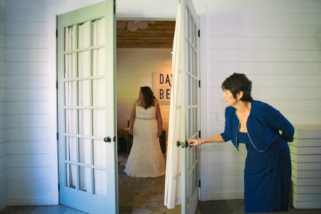 A mother of the bride opening a door and peaking in on her daughter about to wed