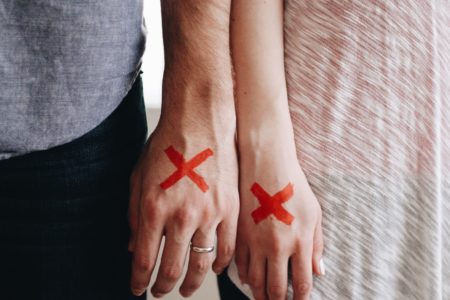 a couple stand side by side with red X's on their hands