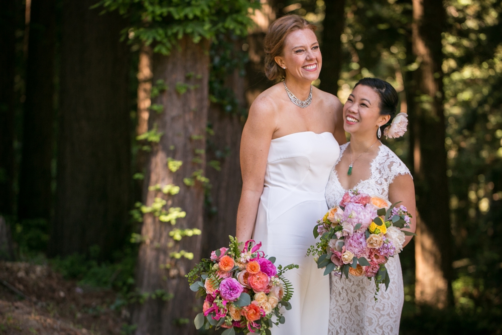 A wedding couple stand and smile in a forest