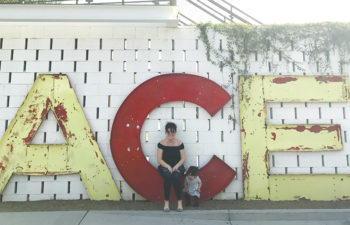 A woman and child sit near letters spelling out ACE