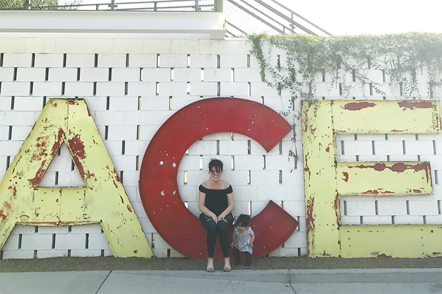 A woman and child sit near letters spelling out ACE
