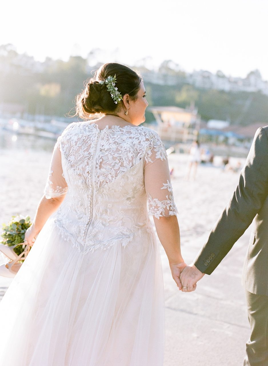 A wedding couple hold hands and walk