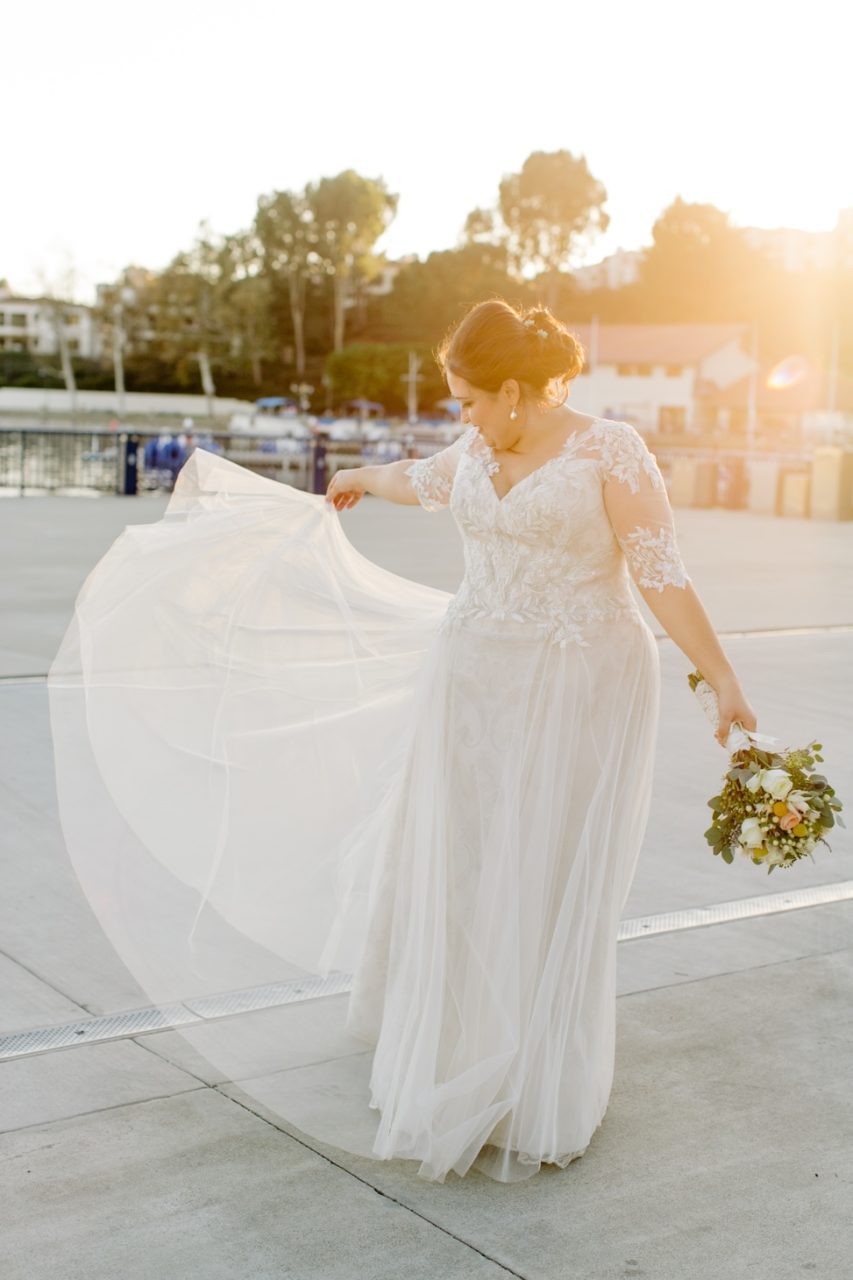 A woman shows off her wedding dress in the sunset light.