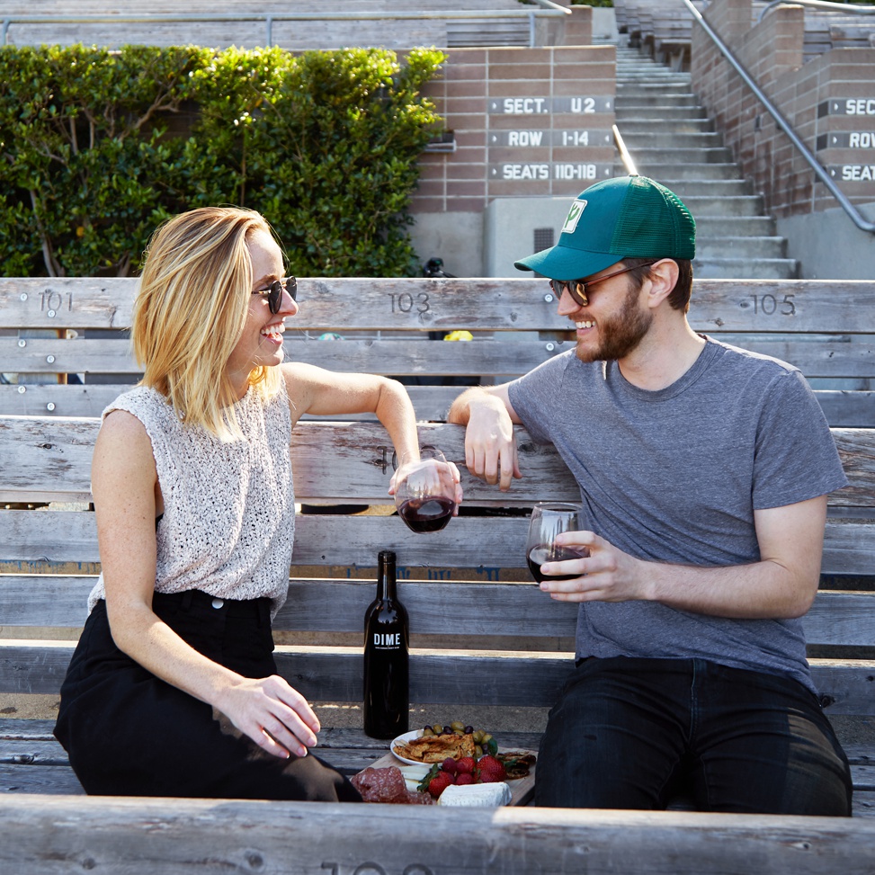 Two people sitting on a bench, happily enjoying some Winc wine