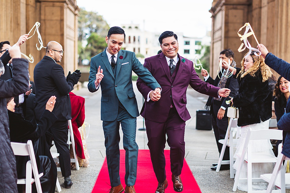 Two grooms walk down the asile