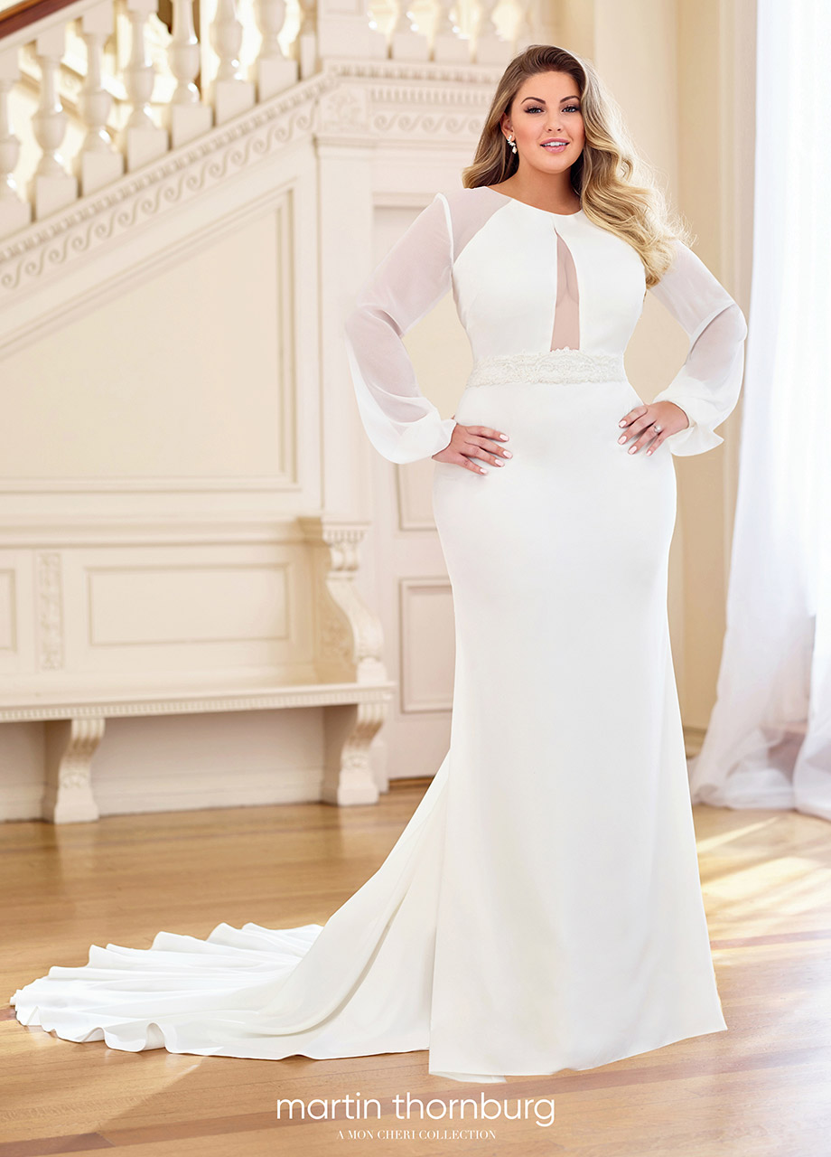 plus size blonde woman wearing a cut-out, sheer, belted wedding dress standing with her hands on her hips