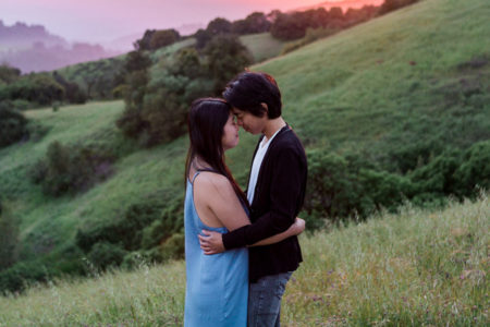 A couple hugs on a mountainside while thinking about engagement anxiety