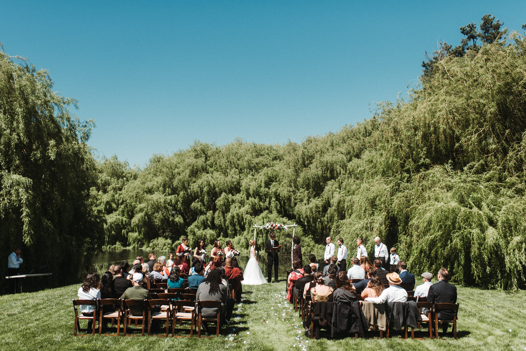 A wedding ceremony takes place on a sunny cloudless day. Small shindigs