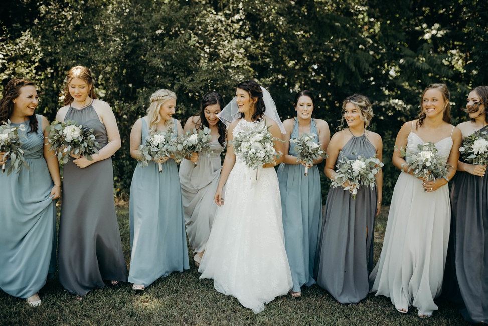 A bridal party stand together with grey and slate blue dresses