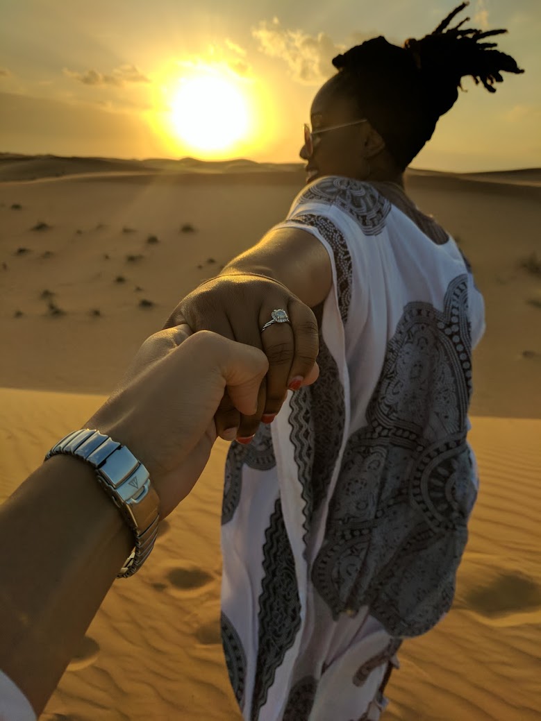 A couple walk hand in hand across the desert