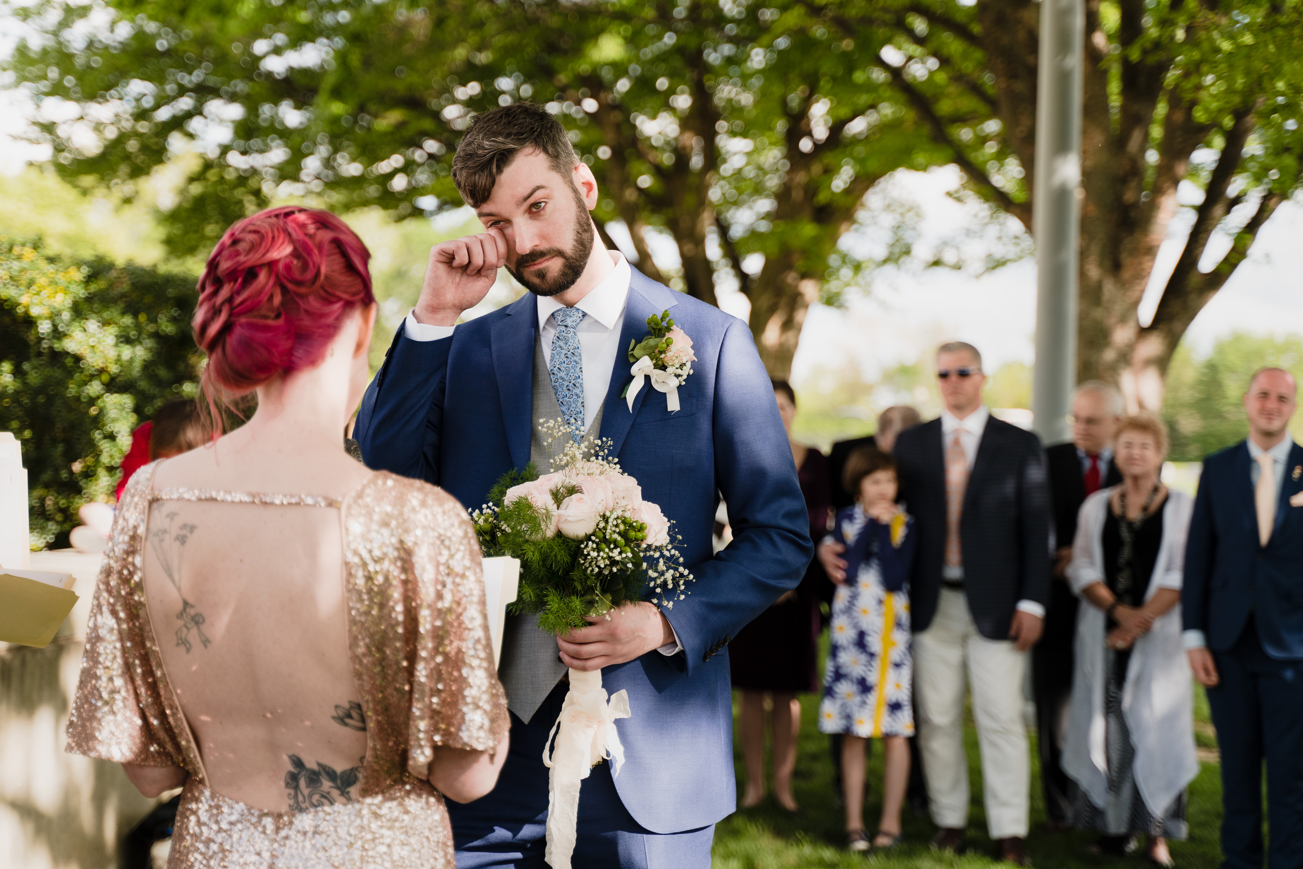 A man tears up as his bride reads her wedding vows during their wedding ceremony