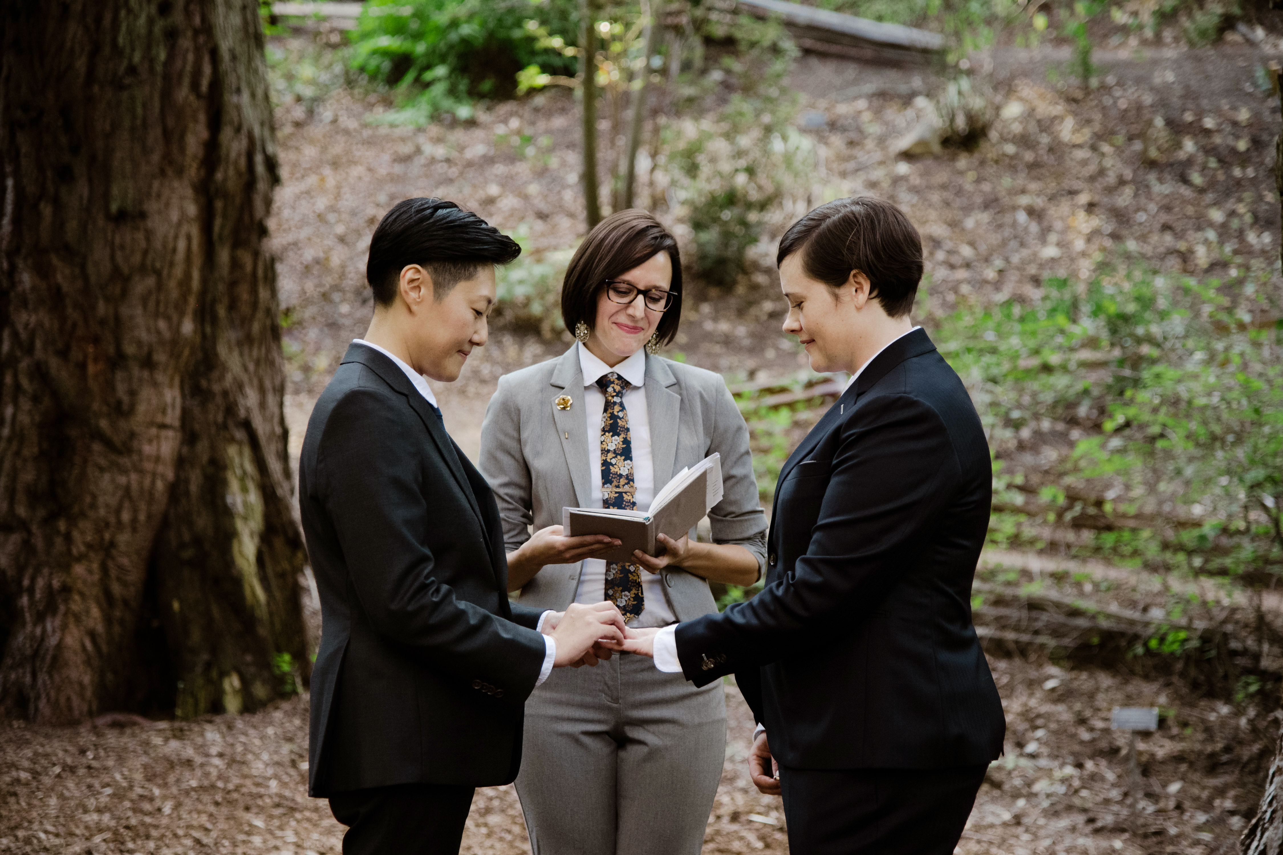 Three people wear suits during a wedding ceremony