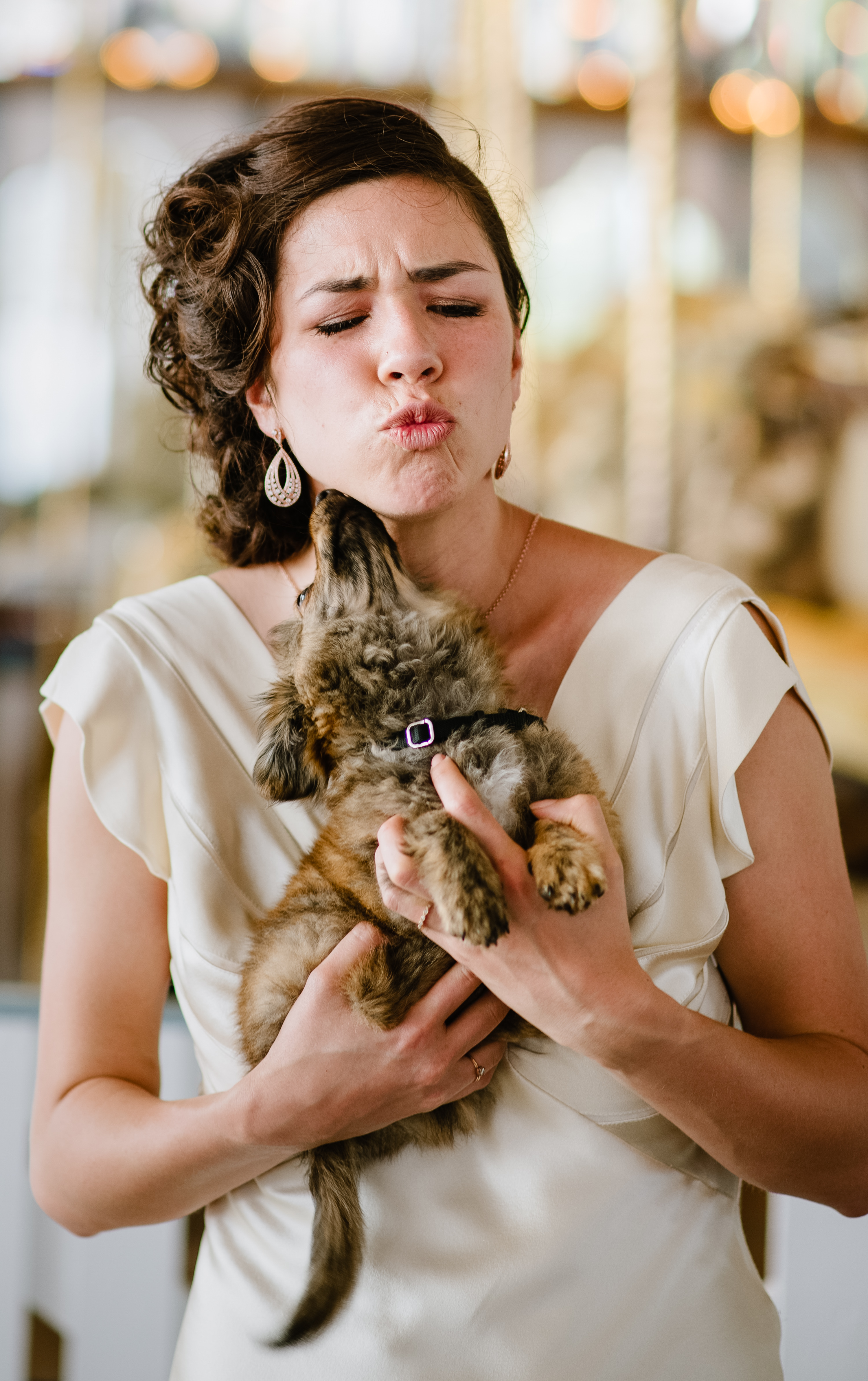 A woman holds a puppy as it kisses her jaw