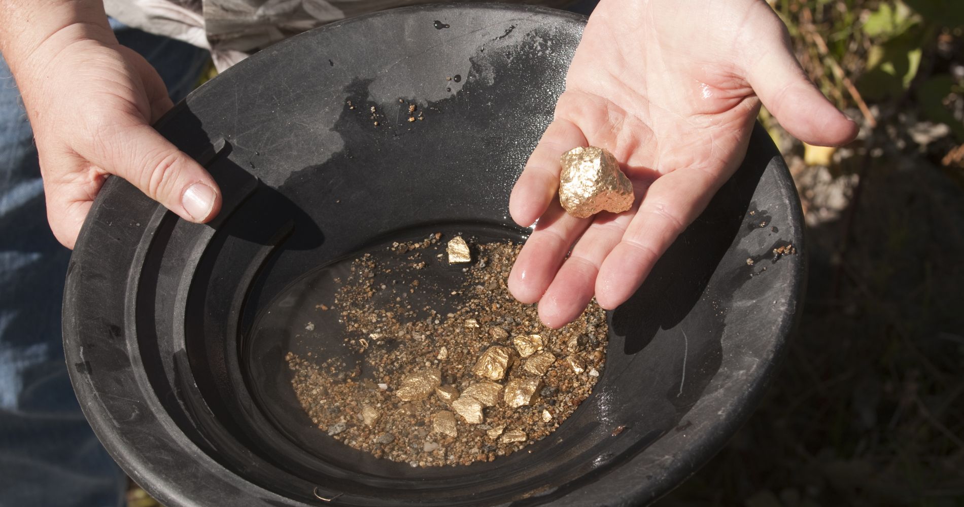 a pair of hands holds gold during a panning experience in Alaska as part of a tinggly wedding experience gift
