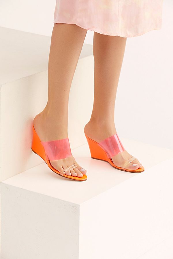 A pair of orange colored wedge shoes