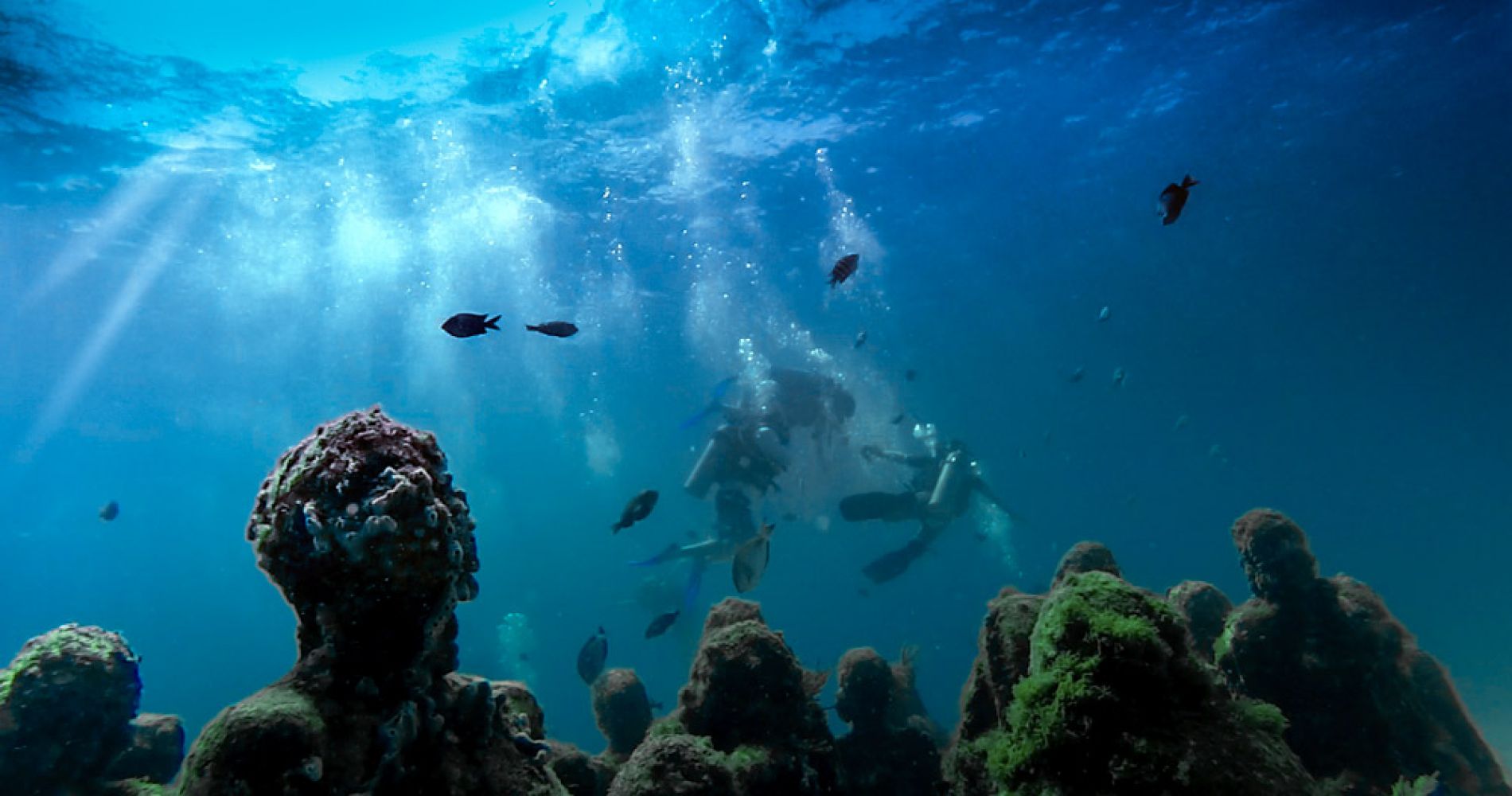 a couple scuba dives in the underwater museum in cancun as part of a tinggly experience gift