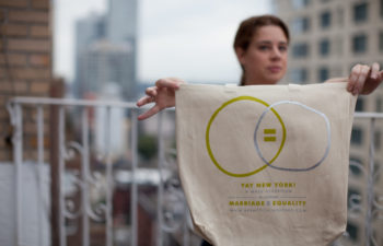 Meg holds up a tote bag