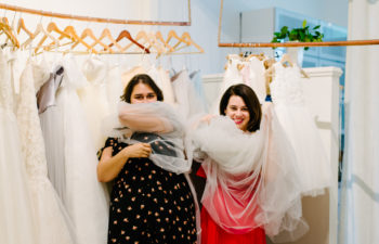 Two women swathed in tulle at a bridal shop