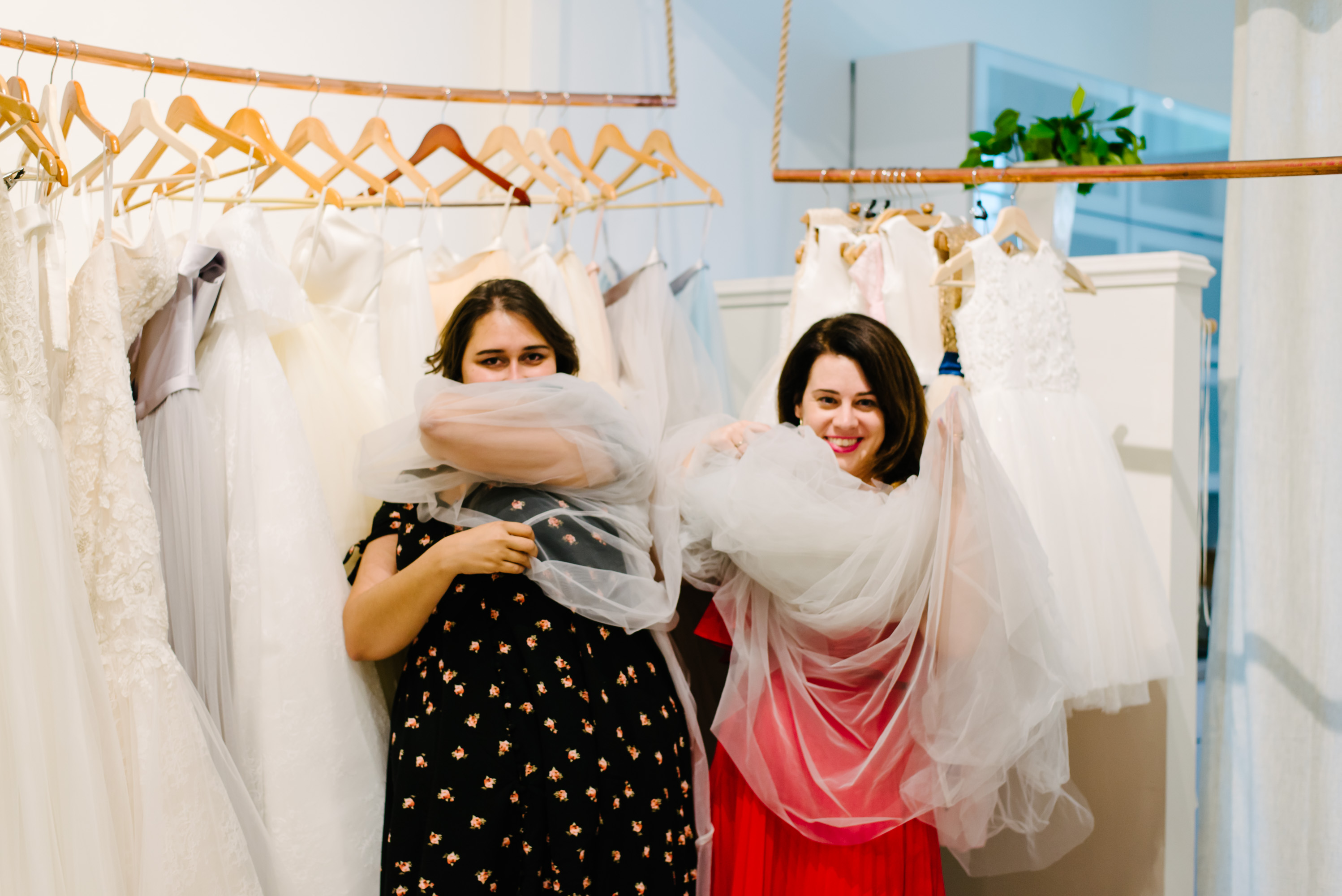 Two women swathed in tulle at a bridal shop