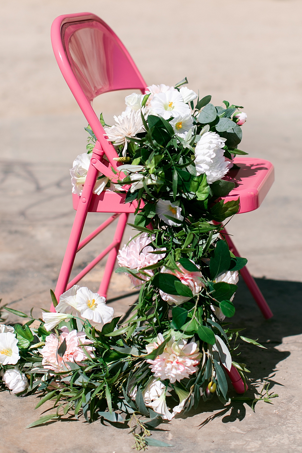 greenery and fake wedding flower whip bouquet laid on a bright pink chair - the Rogue Petal Co.