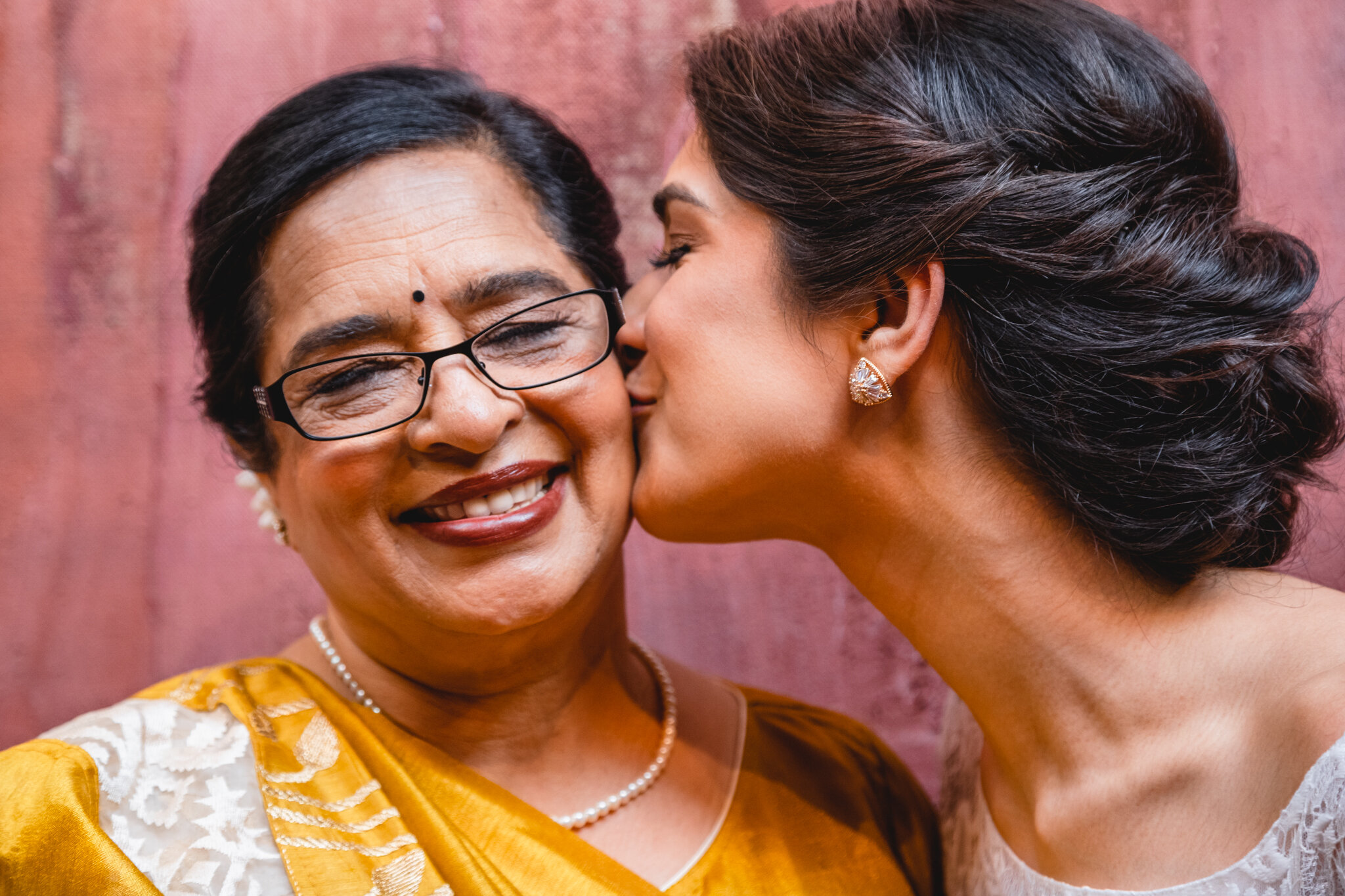A woman kisses her mother's cheek.