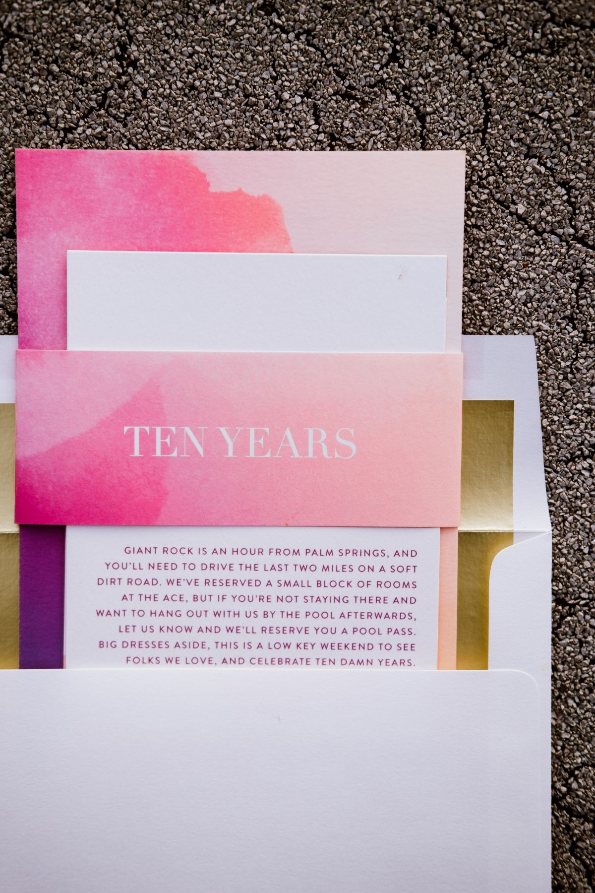 a close up of a layflat of a Minted reptured wedding suite in hot pink with gold foil envelop liner and watercolor accents