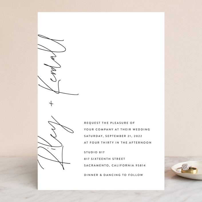 Simple black font on white wedding invitation with names that look hand-scripted on the left side vertically.