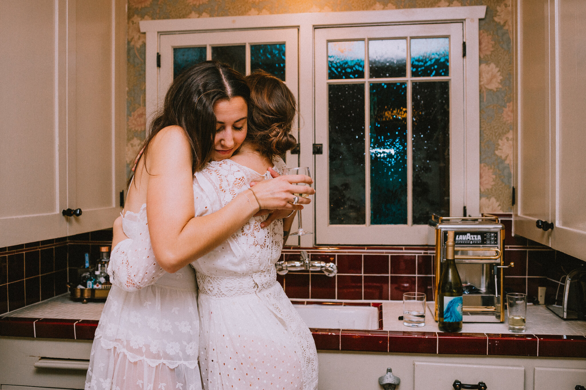 Two women embrace in the kitchen.