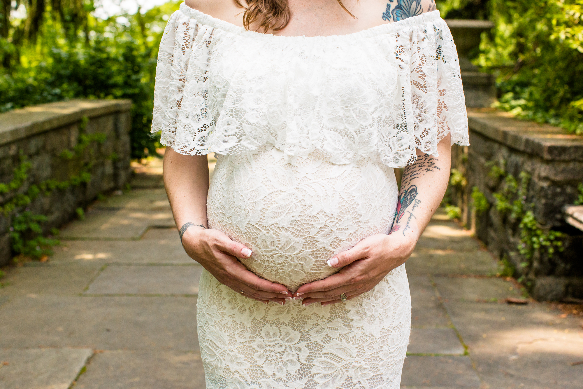 Closeup of a woman holding her pregnant belly while wearing a wedding dress.
