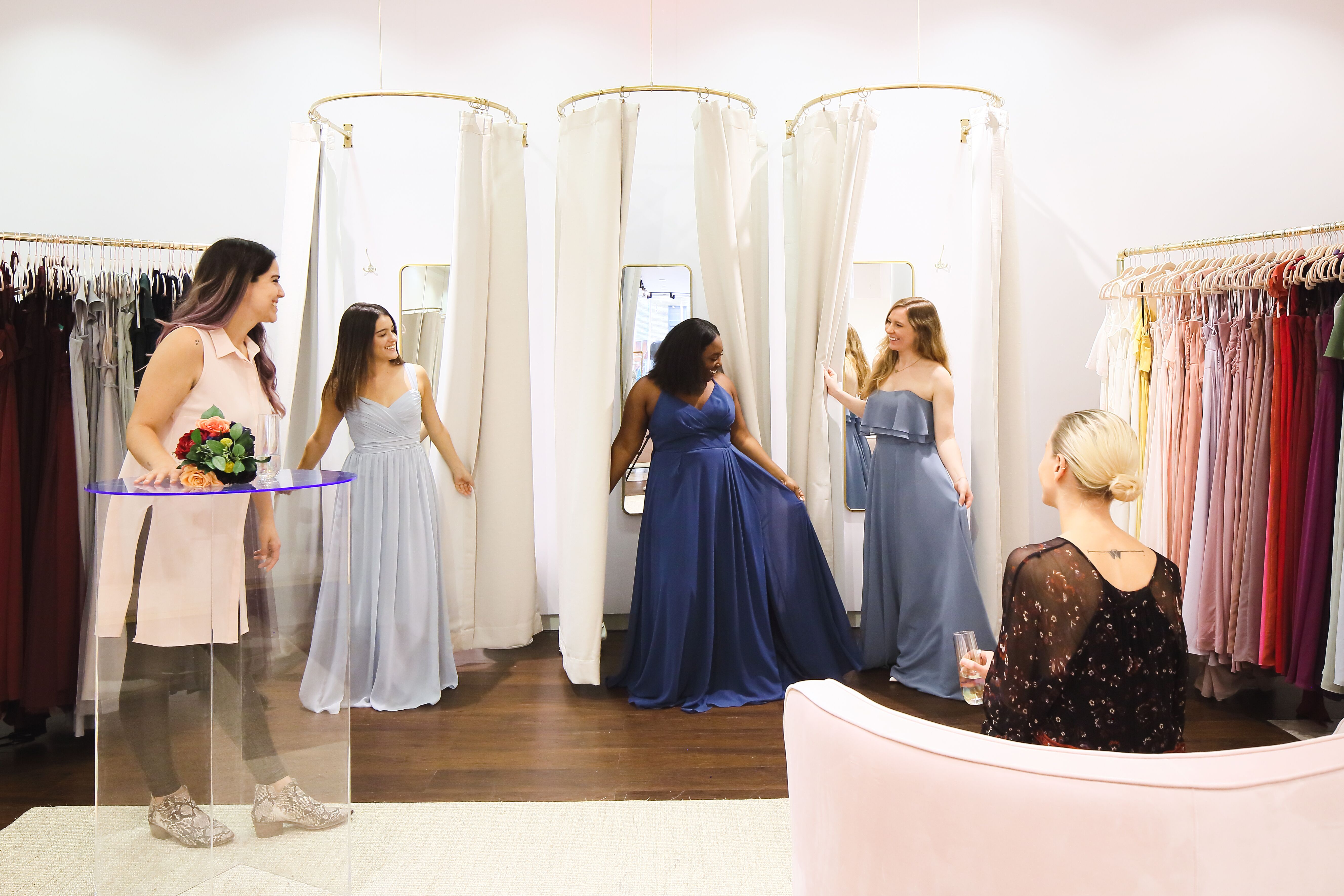 Women in a store are trying on bridesmaid dresses.