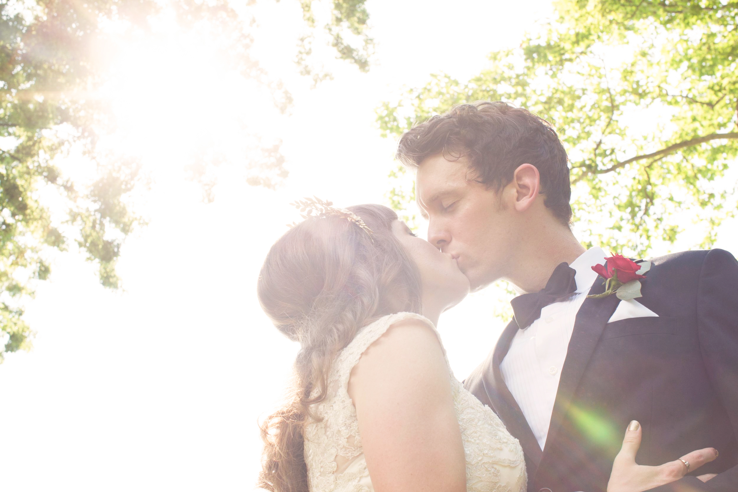 A wedding couple kiss in the forest.