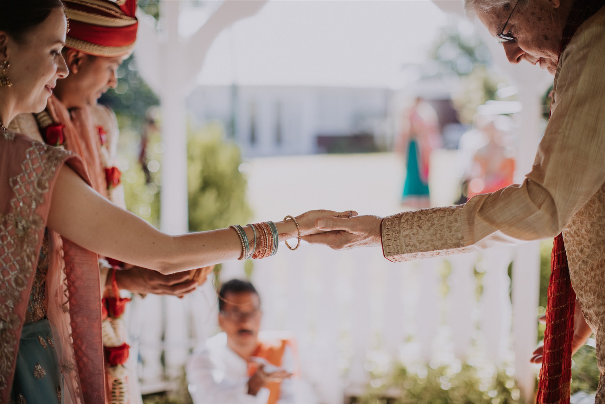 Two persons gently hold hands during a wedding ceremony. Photo by The Commoneer.