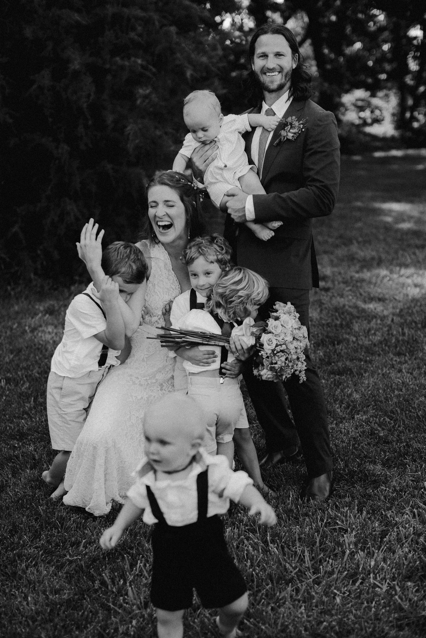 A man and woman laugh and embrace several babies and children.