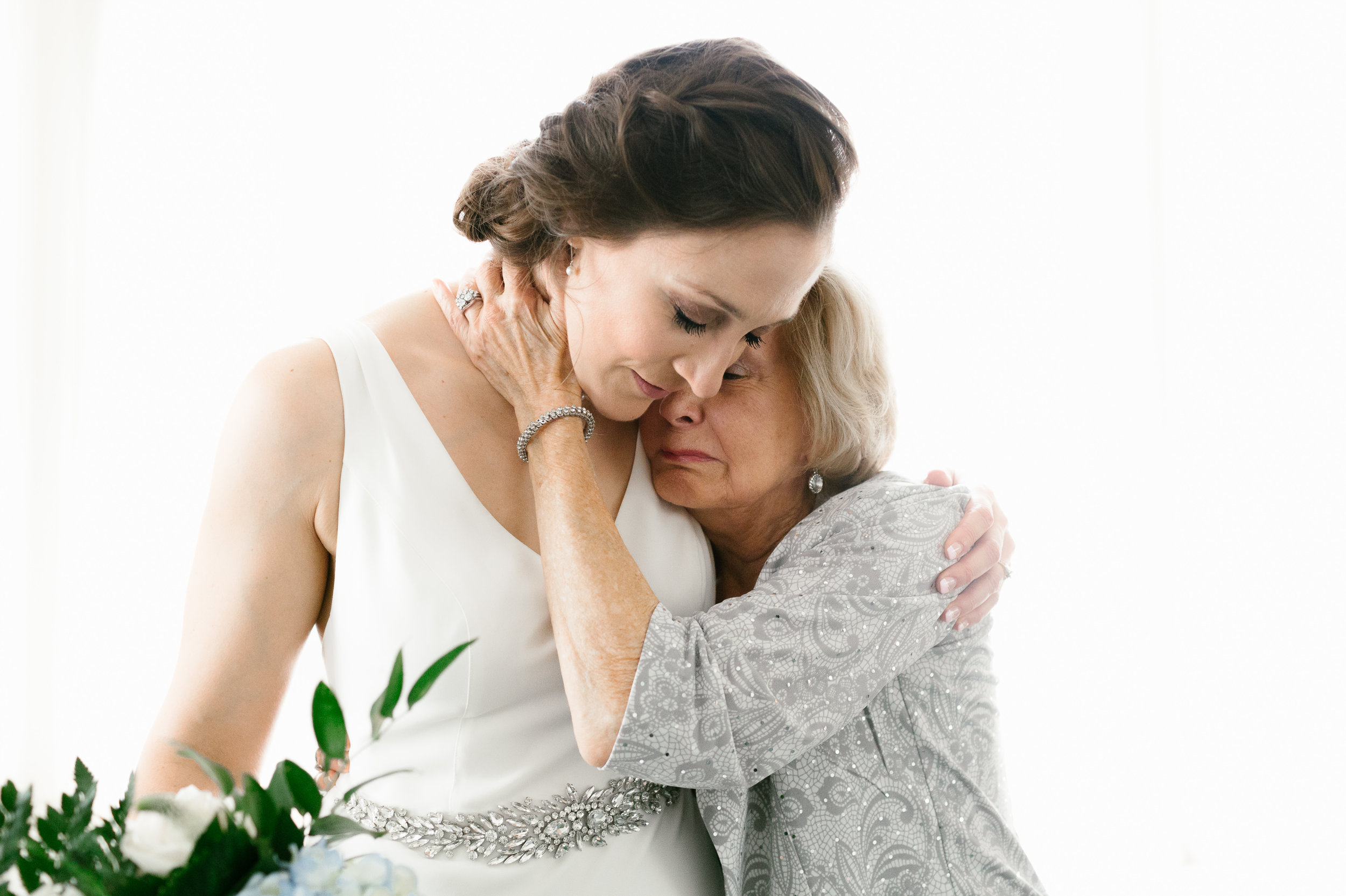 A bride and an older woman embrace.