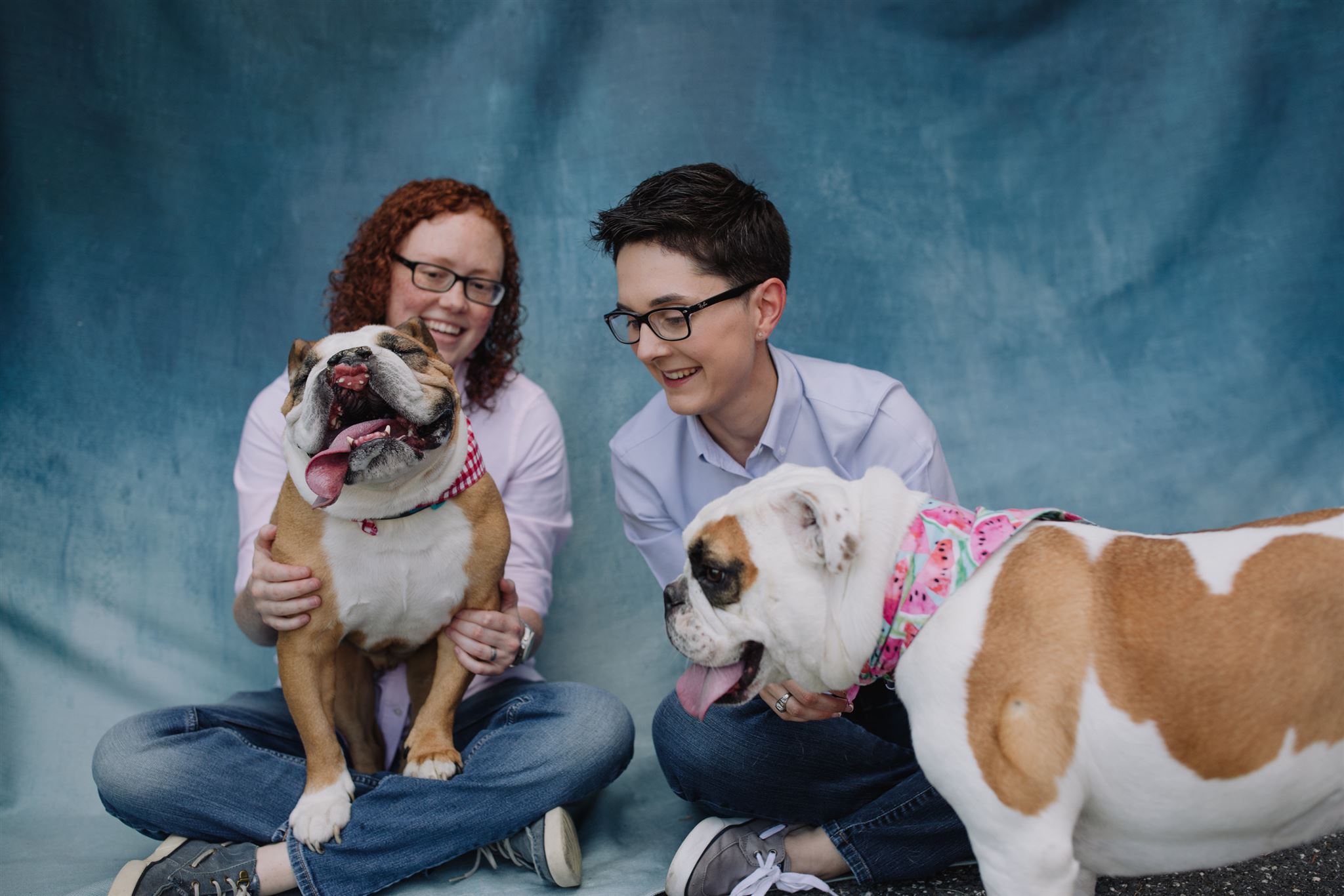 Two persons sit for a portrait with their two dogs.