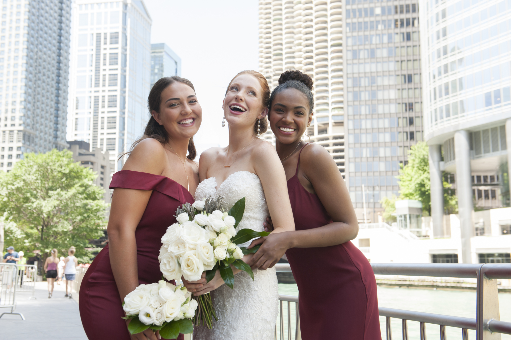 A bride is surrounded by a bridesmaid on each side as they laugh.