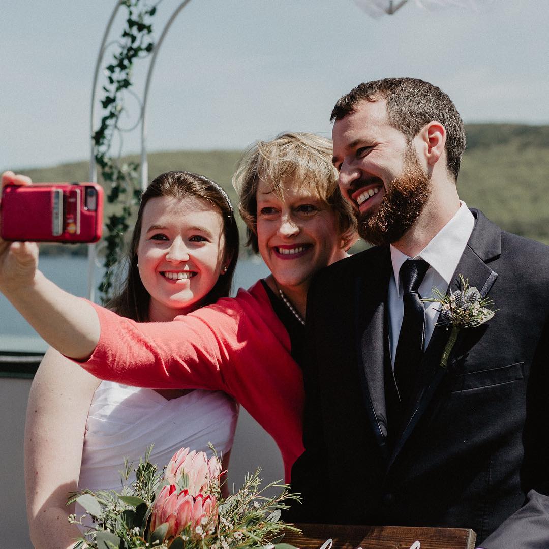 A wedding couple and their officiant take a selfie.