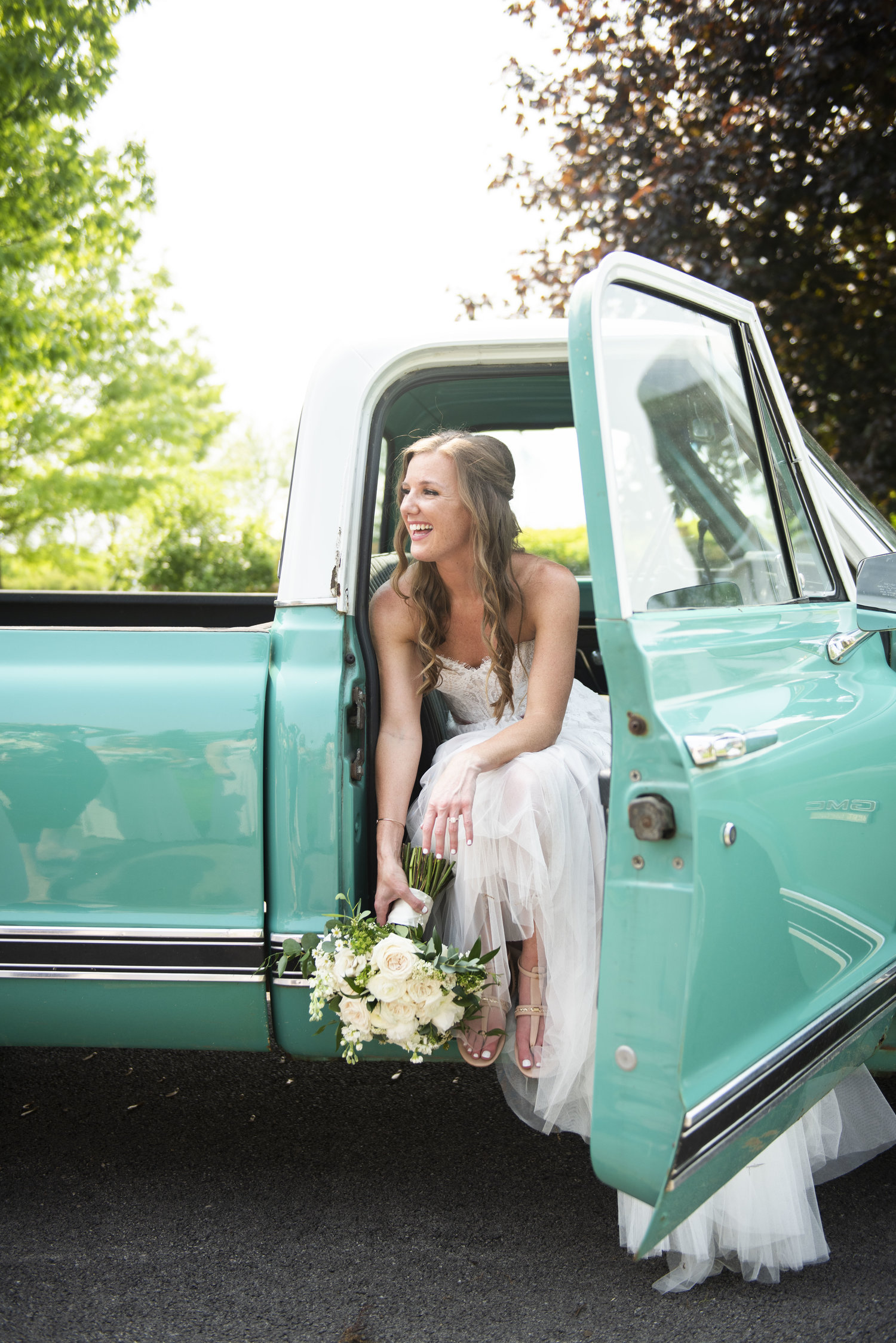Bride sits in the passenger seat of a truck.