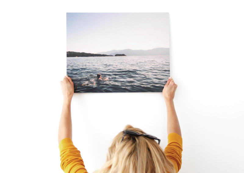 A woman holds up a metal print.