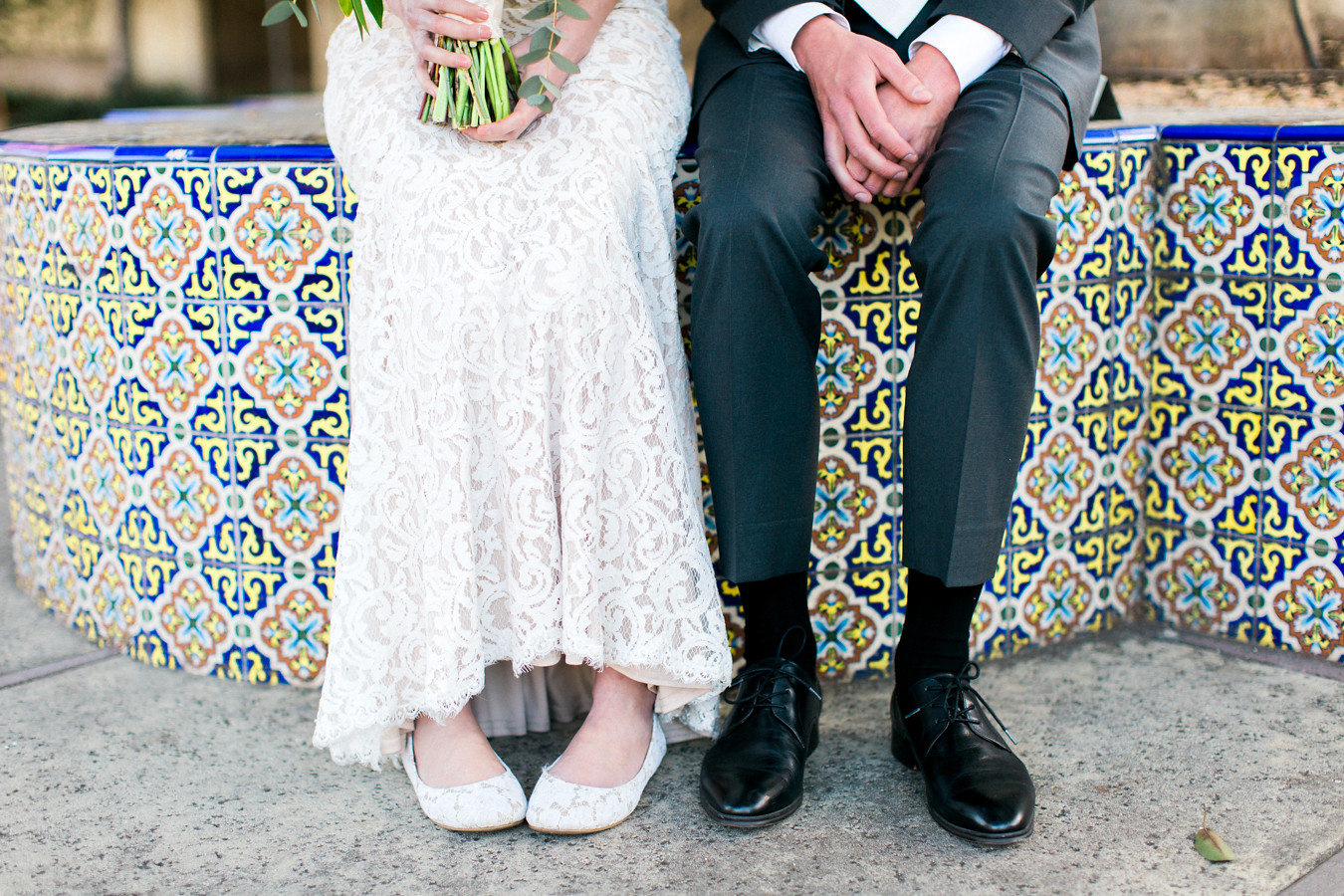 bride and groom's legs show while sitting on colorful tiles