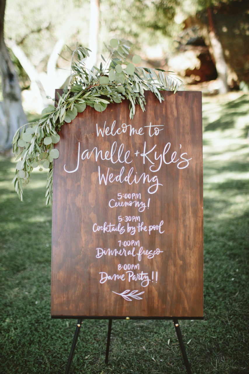 A wood board with a wedding schedule printed on it.