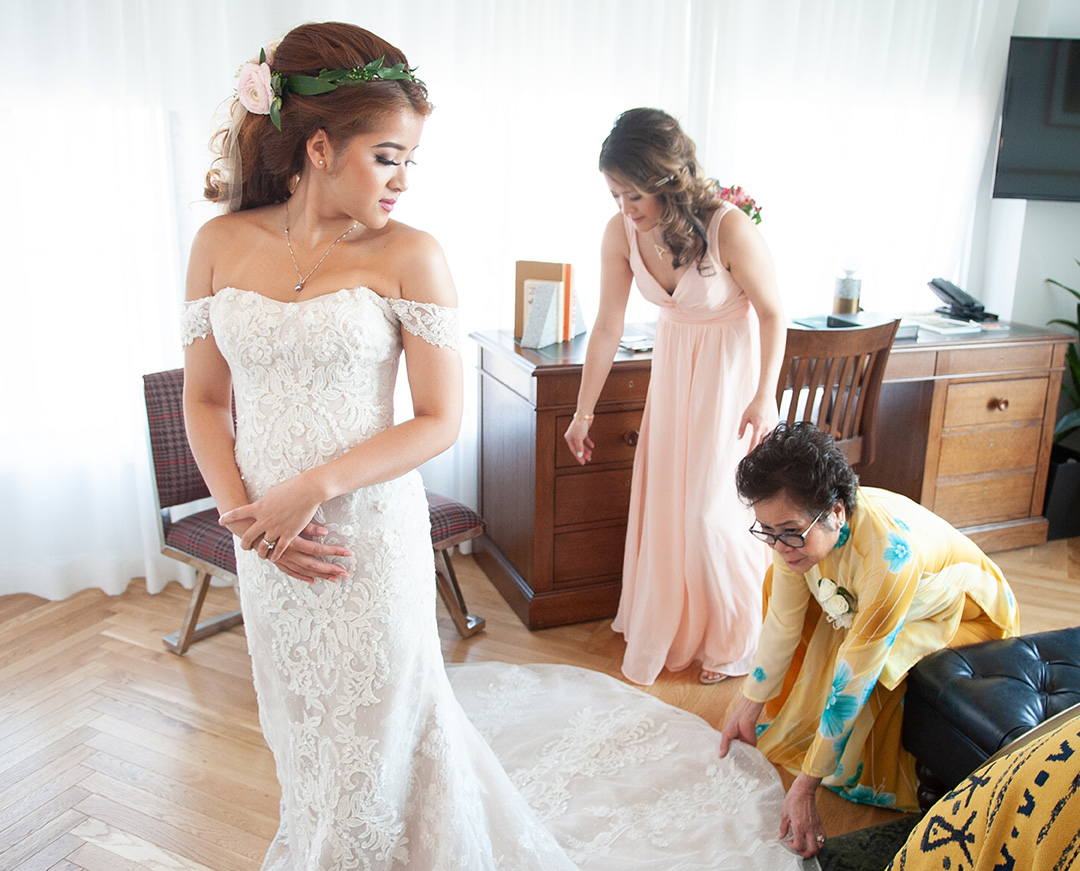 A mother helps a bride into her dress.
