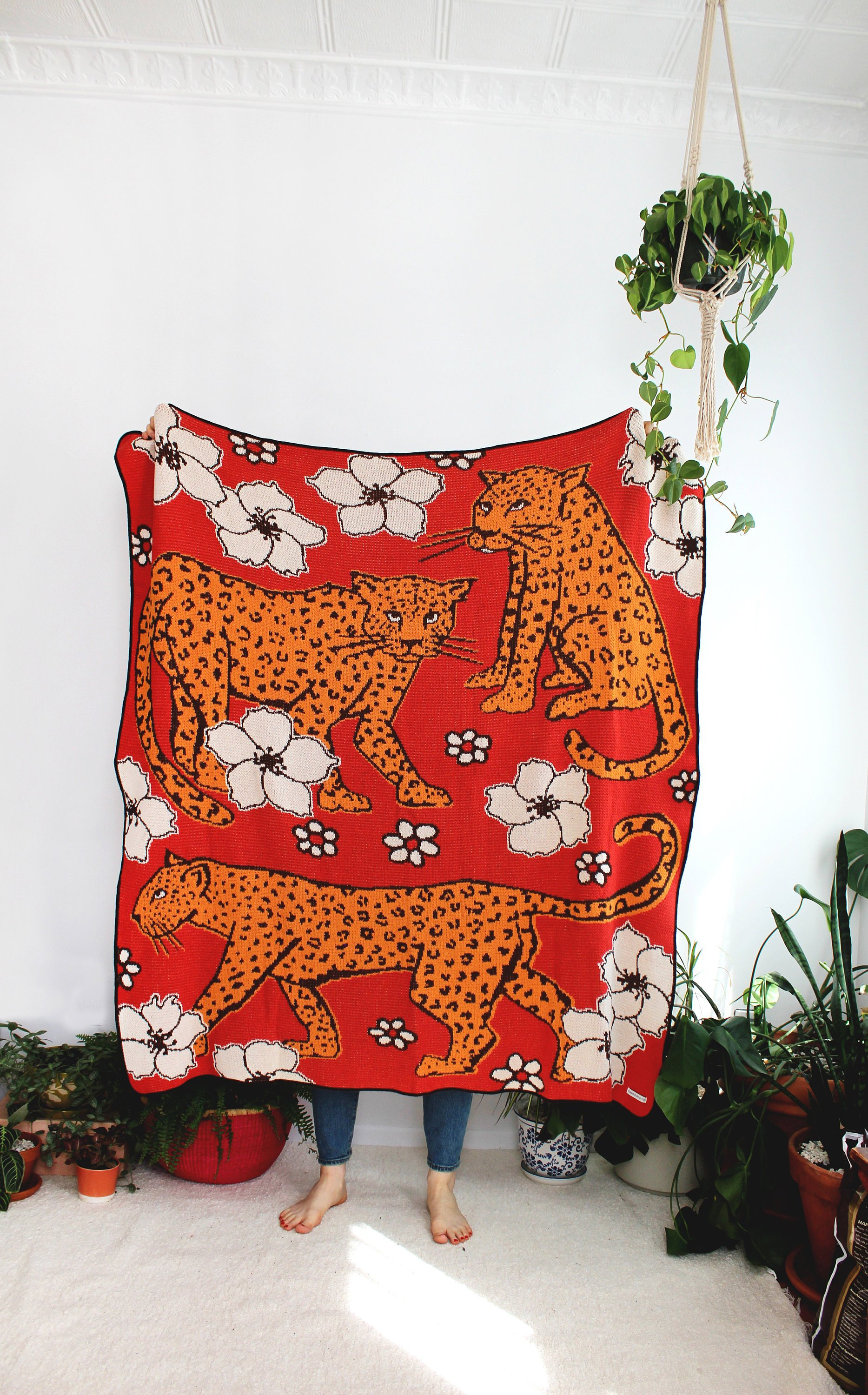 A blanket with leopards in a flower patch printed on it.